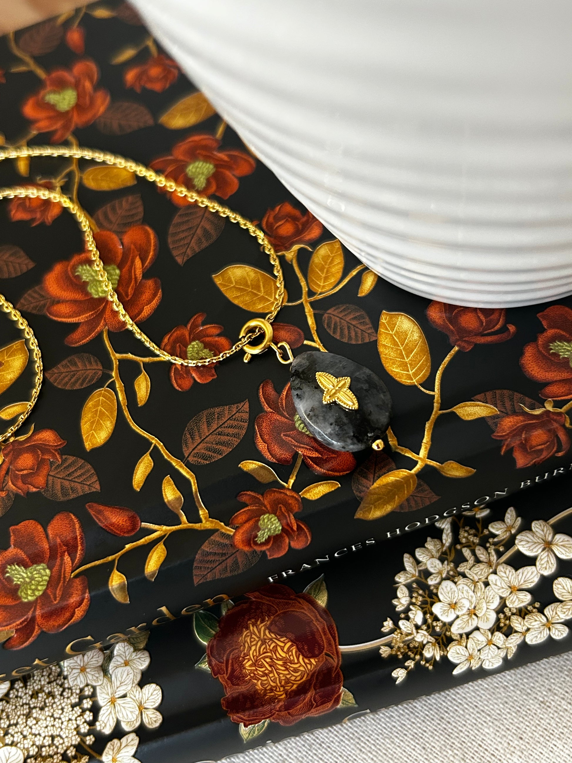 Close-up of a cross necklace with floral patterns and jewelry on a black background.