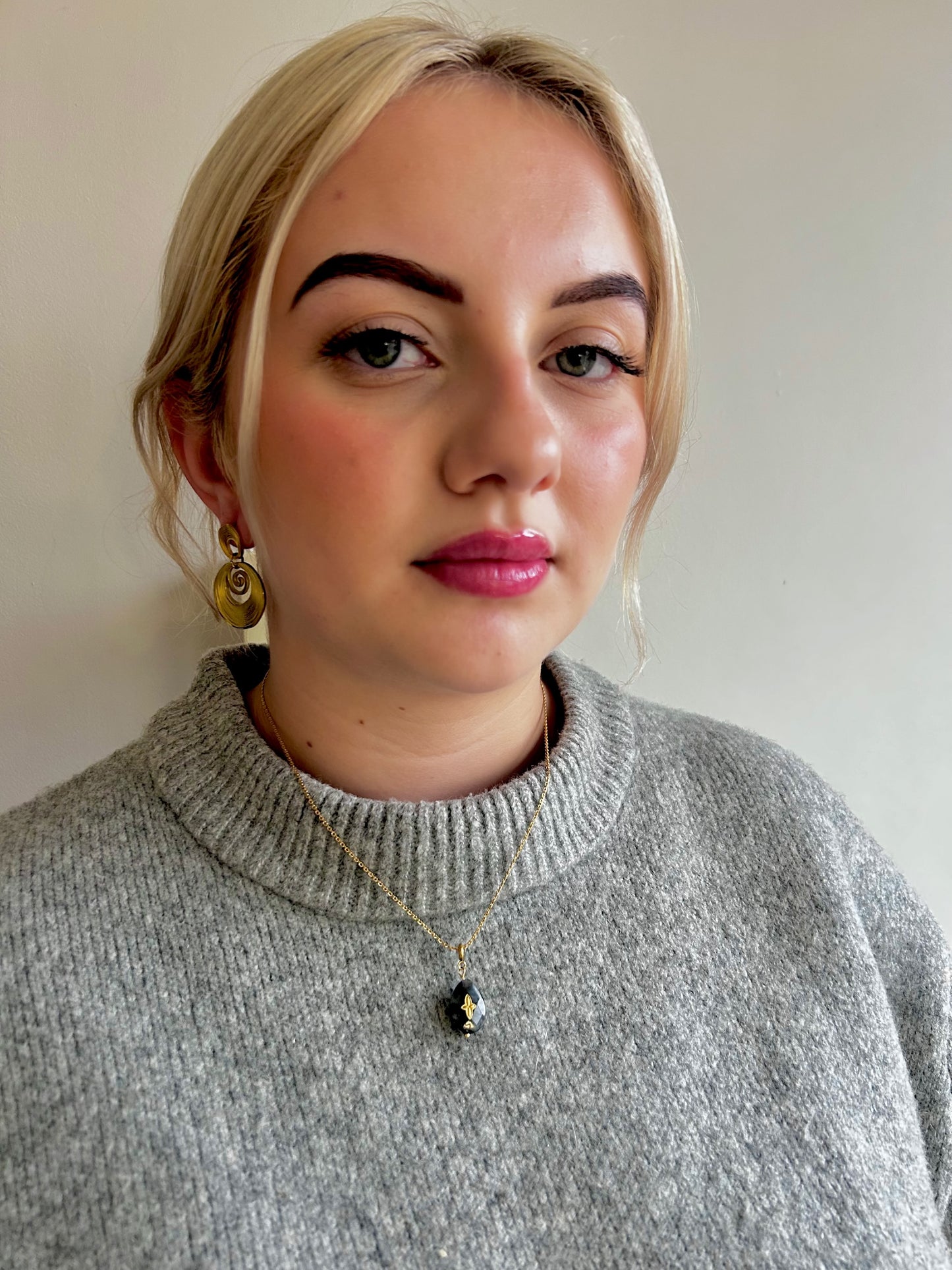 Woman wearing a gray sweater with fashionable gold Jessica & James jewellery