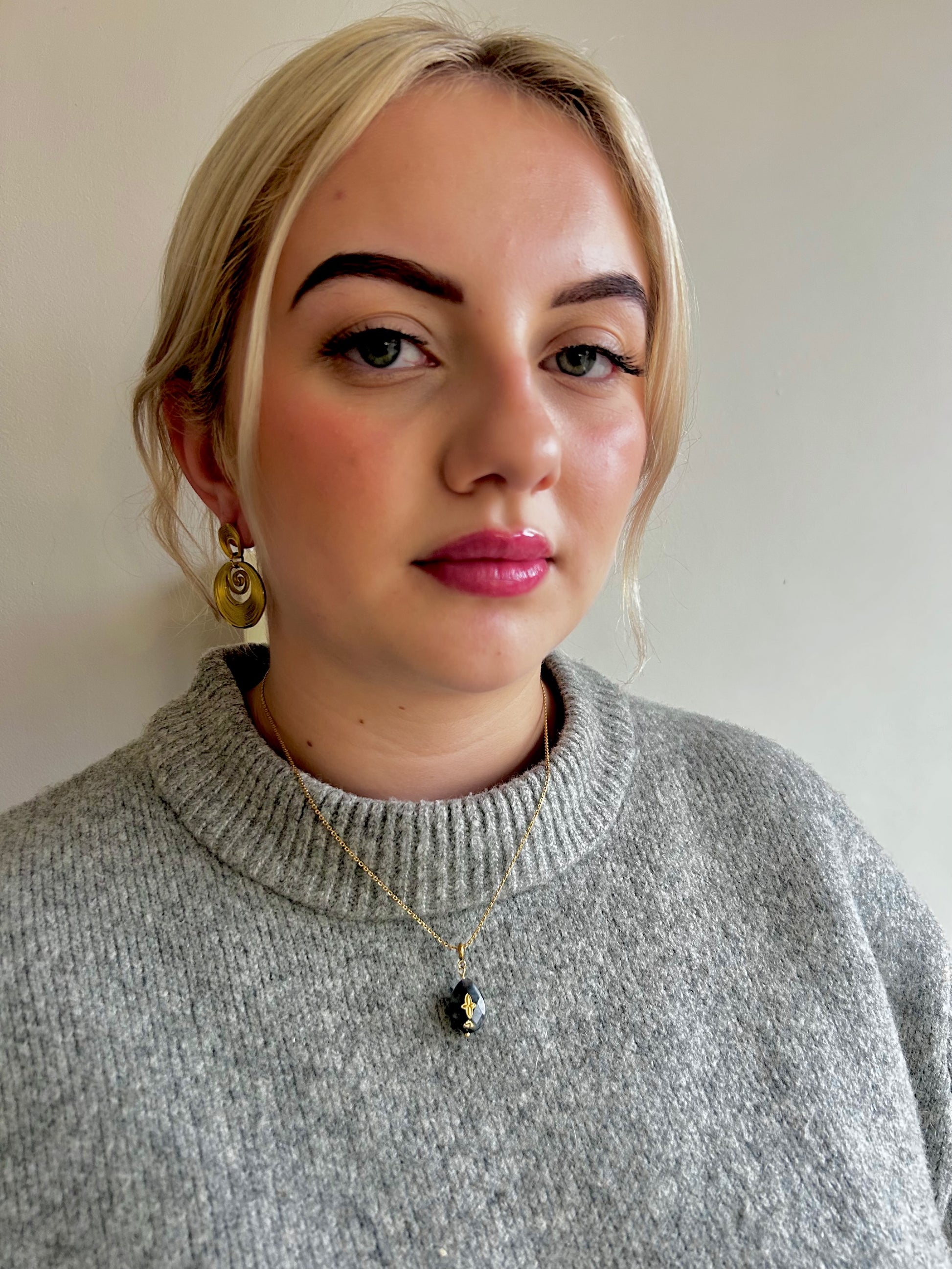 Woman wearing a gray sweater with fashionable gold Jessica & James jewellery