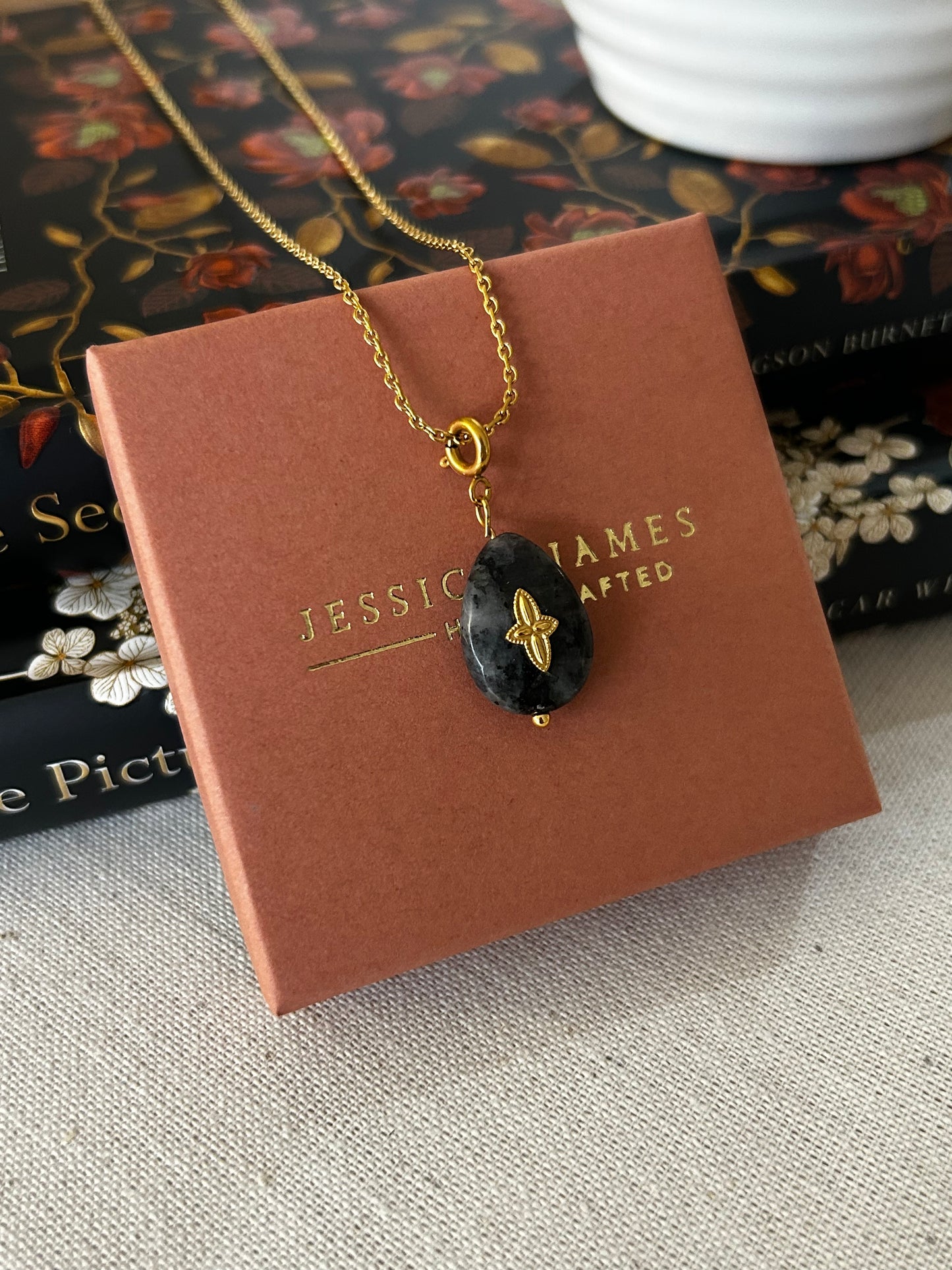 Necklace with a black cross pendant with  'Jessica James' branding