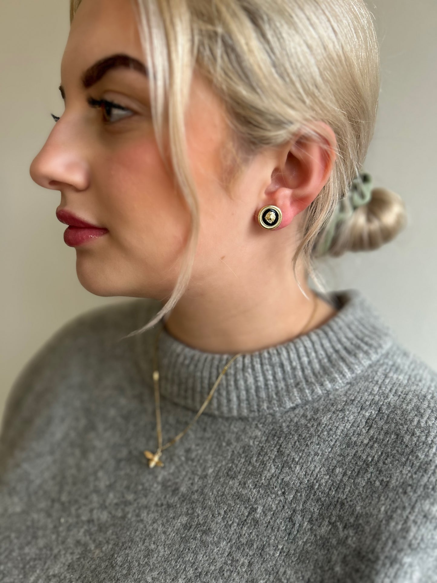Woman wearing a gray sweater with a close-up of her ear showing an earring.