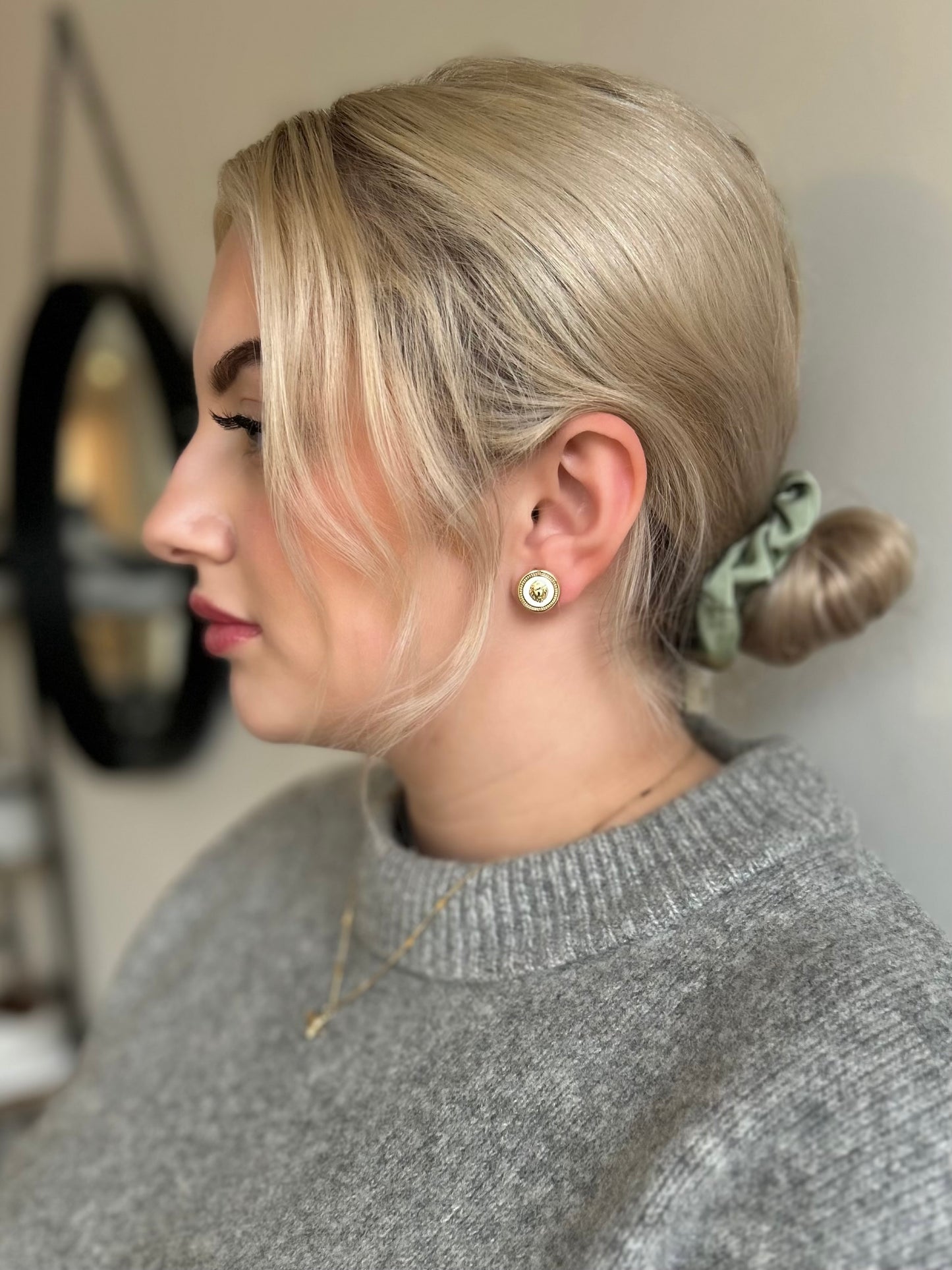Woman with styled hair and a gray sweater in a neutral setting