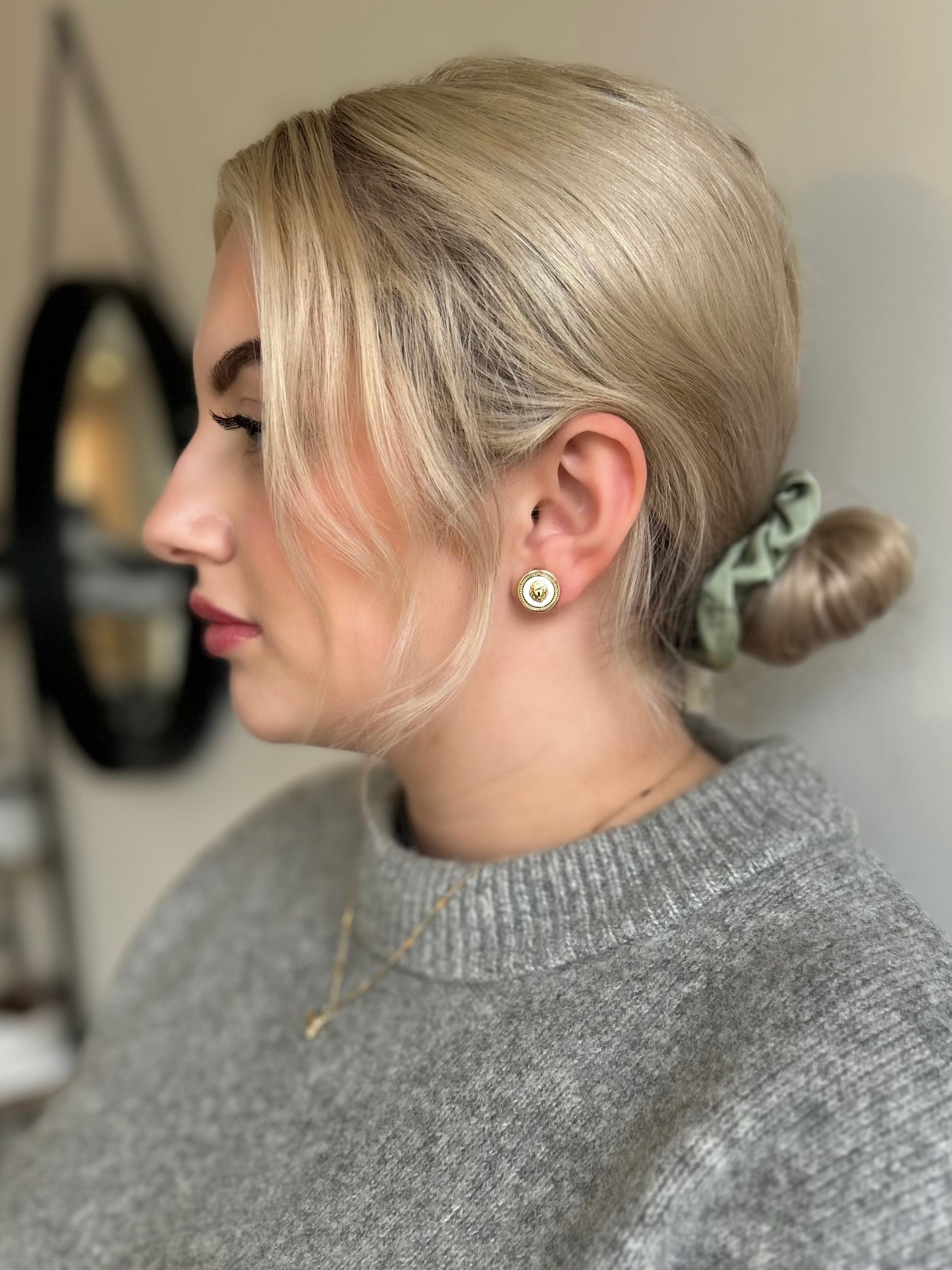 Woman with styled hair and a gray sweater in a neutral setting