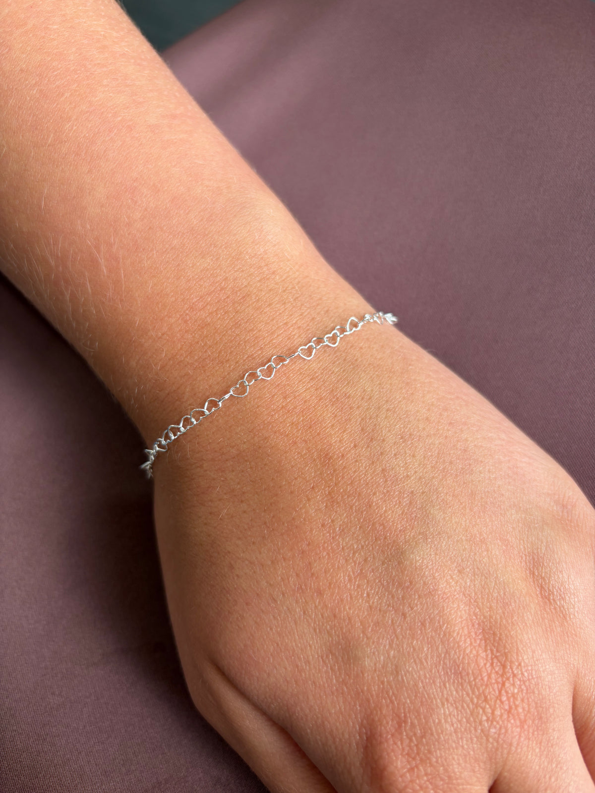 A delicate silver bracelet kit with heart chain, shown worn on a person's wrist at home kit. Perfect jewellery gift idea