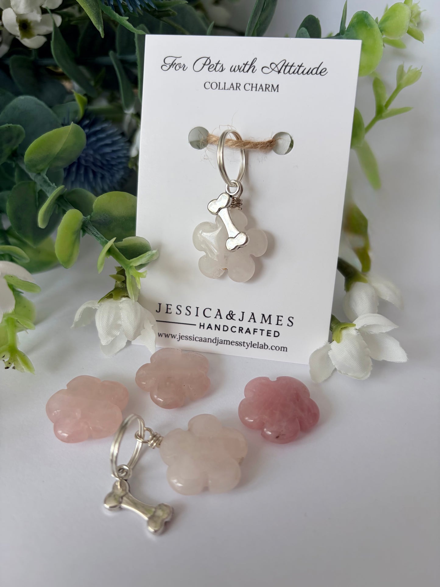A pet collar charm displayed on a white card labeled 'For Pets with Attitude' and 'COLLAR CHARM,' with the brand name 'JESSICA&JAMES' visible. The charm is a pale pink translucent flower-shaped piece with a silver bone-shaped clasp.