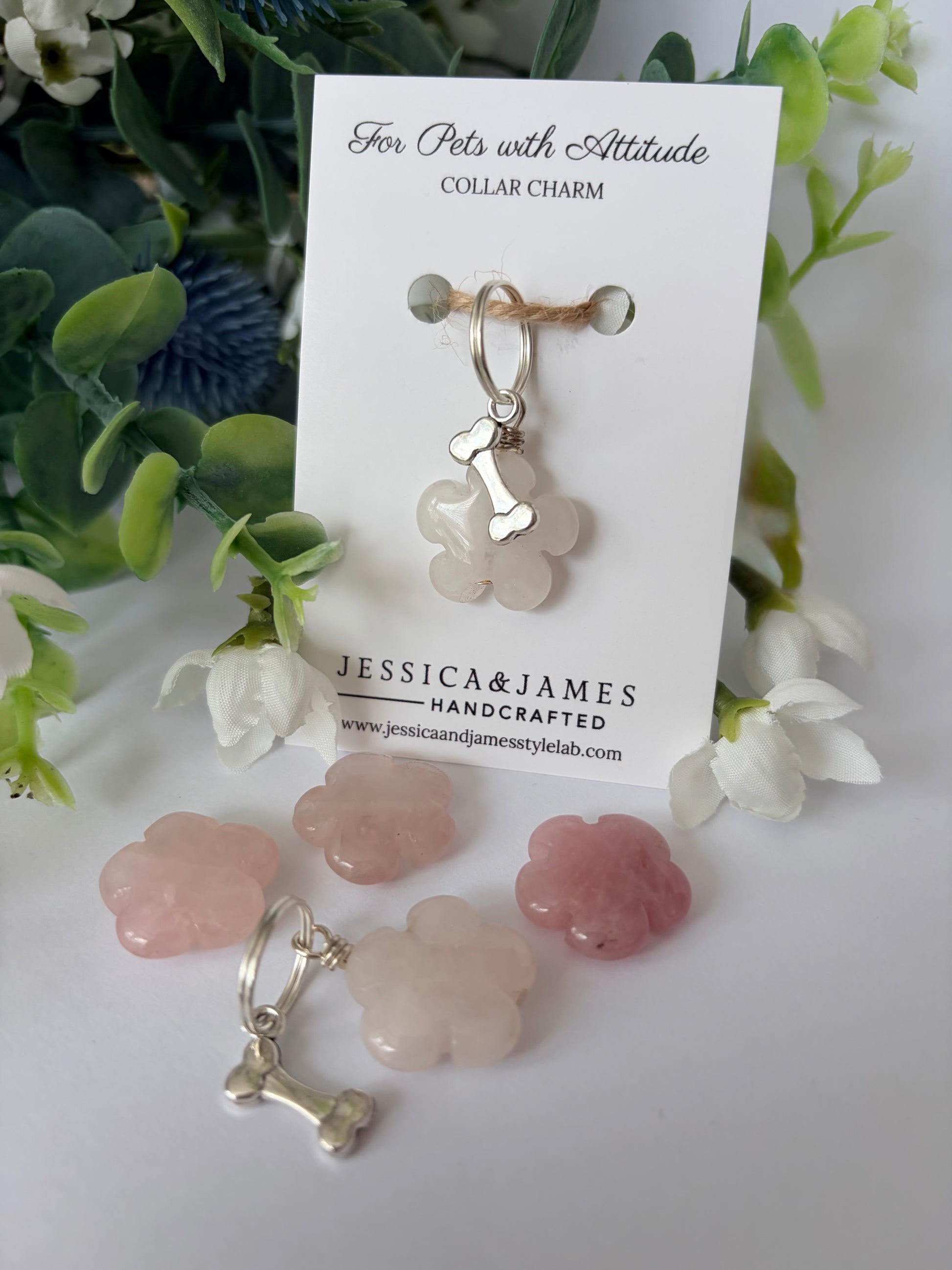 A pet collar charm displayed on a white card labeled 'For Pets with Attitude' and 'COLLAR CHARM,' with the brand name 'JESSICA&JAMES' visible. The charm is a pale pink translucent flower-shaped piece with a silver bone-shaped clasp.